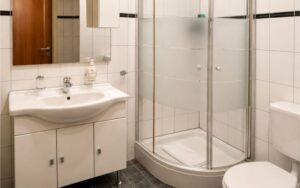 Modern Verdo Hotel double room bathroom with glass corner shower, clean sink vanity, and bright white tiled boutique interior.