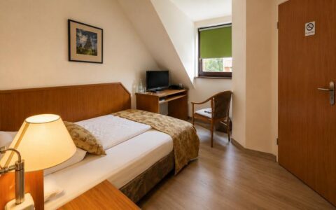Verdo Hotel deluxe room with cozy bed, warm bedside lamp, wooden furniture, and bright boutique-style interior.