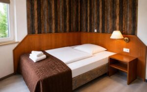 Warm Verdo Hotel deluxe room with cozy single bed, wooden furniture, bedside lighting, and classic boutique hotel atmosphere.