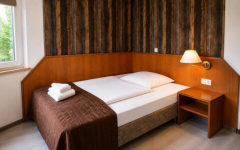 Warm Verdo Hotel deluxe room with cozy single bed, wooden furniture, bedside lighting, and classic boutique hotel atmosphere.