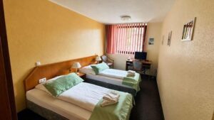 Verdo Hotel double room with twin beds, warm lighting, workspace desk, and comfortable boutique hotel interior.