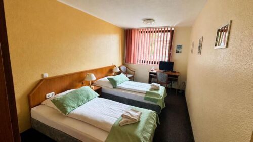 Verdo Hotel double room with twin beds, warm lighting, workspace desk, and comfortable boutique hotel interior.