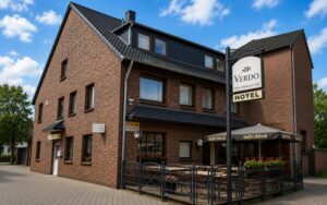 Exterior view of Verdo Hotel building with outdoor terrace seating, brick façade, and boutique hotel entrance in Bergheim-Glessen.