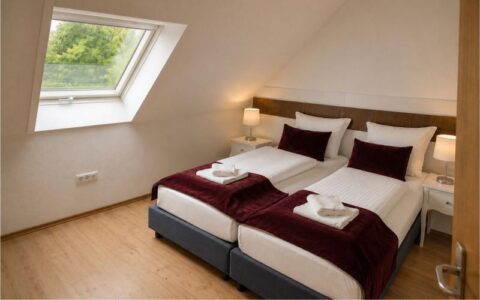 Comfortable Verdo Hotel family room with twin beds, soft lighting, sloped ceiling window, and warm boutique-style interior.