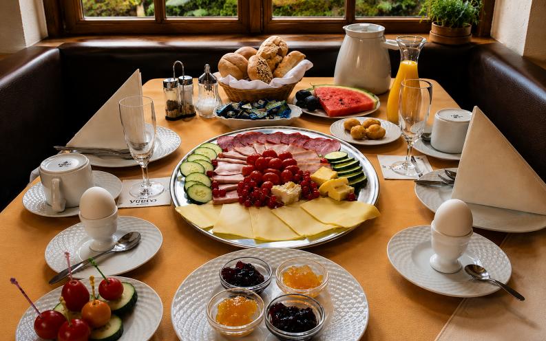 Elegant breakfast spread at Verdo Hotel restaurant with fresh pastries, cheese platter, fruit, coffee, and warm natural morning light.
